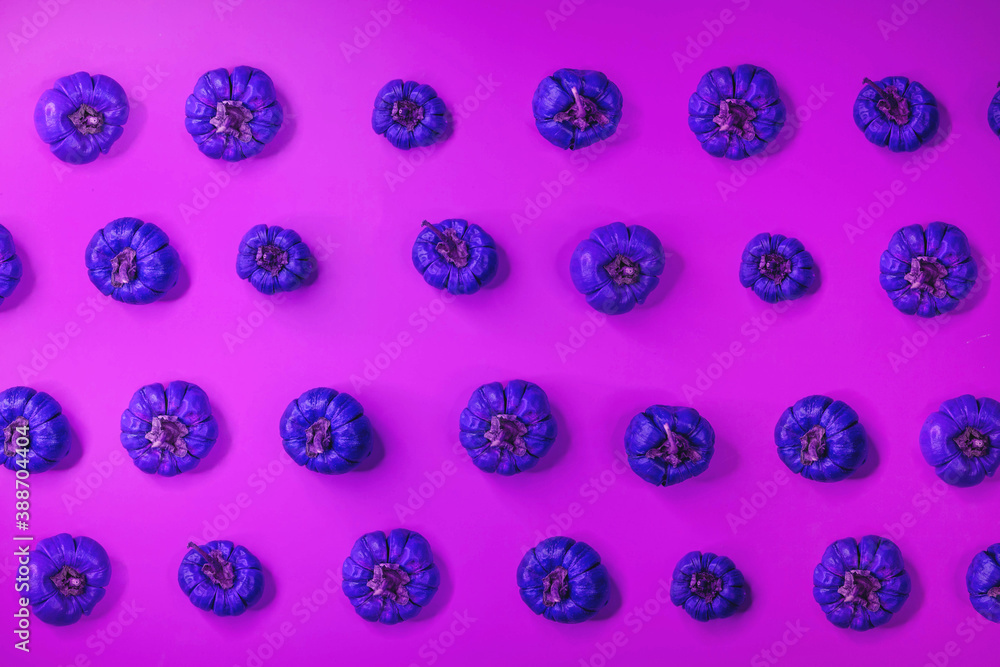 Little pumpkins of artificial purple color over pink background