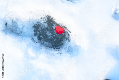 Small red felt heart on the ice and snow. Valentine's Day, winter concept. Greeting or invitation card. Copy space for text.