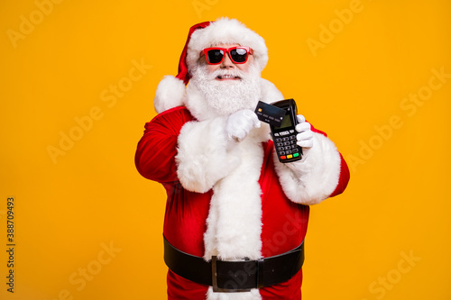 Portrait of his he nice attractive cheerful fat overweight Santa using wireless bank card digital terminal paypass system isolated bright vivid shine vibrant yellow color background
