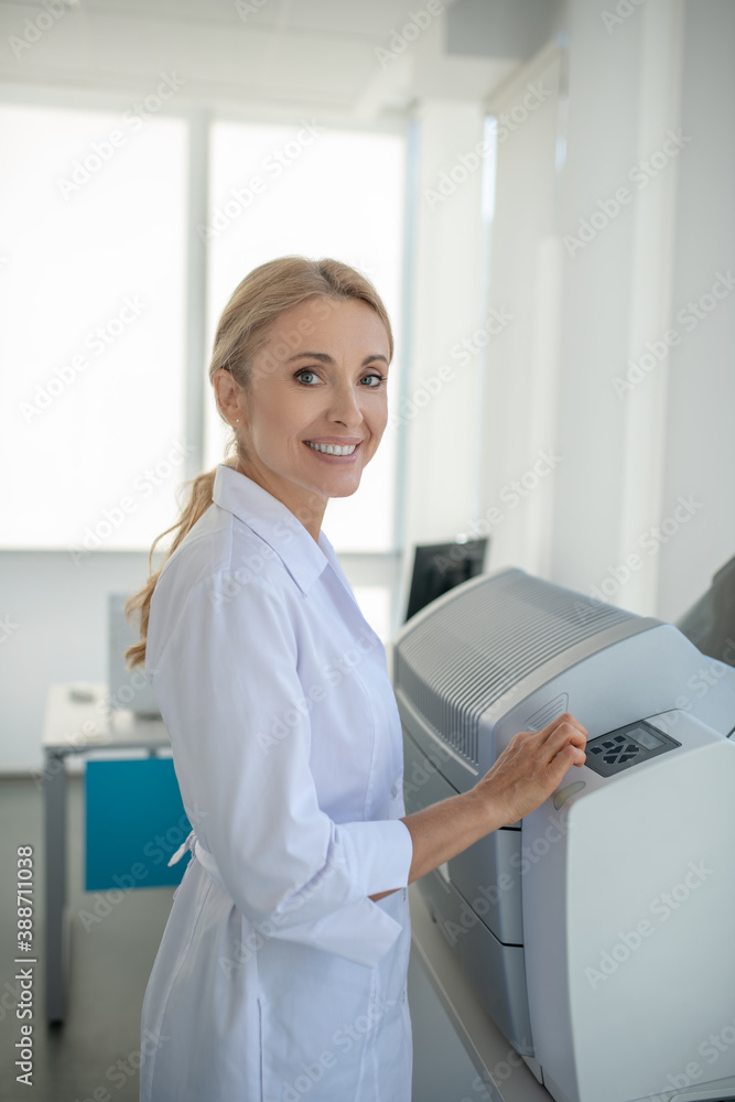 Fair-haired young doctor standing in the office and smiling Fair-haired young doctor standing in the office and smiling