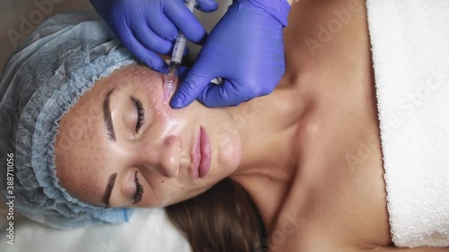 Face mesotherapy procedure in a beauty salon. Beautician doctor makes injections into the skin of the face of a young beautiful woman. Mesotherapy, biorevitalization. Cosmetology.
