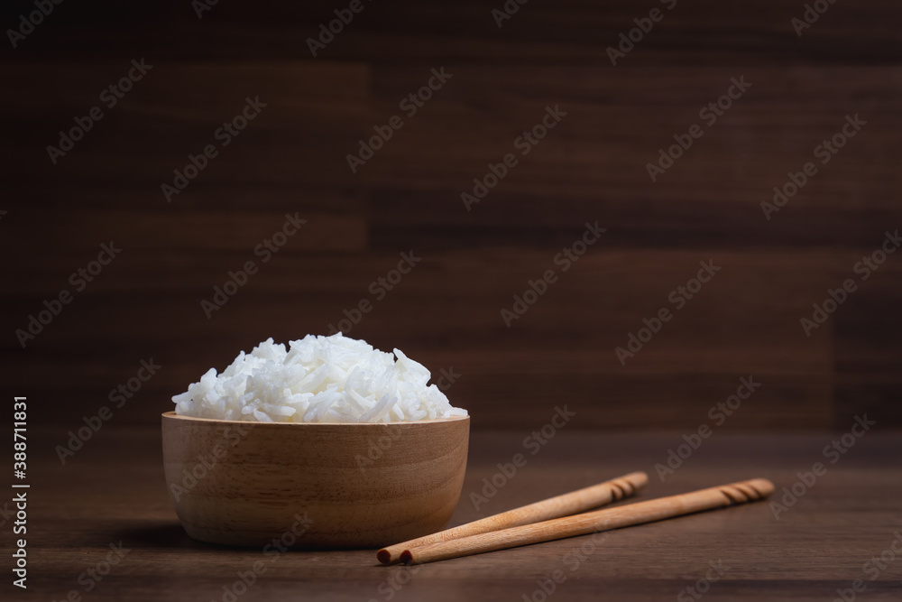 Cooked jasmine rice in wooden bowl with chopsticks on wooden table. Thai Jasmine rice. Cooked jasmine rice in wooden bowl with chopsticks on wooden table. Thai Jasmine rice.