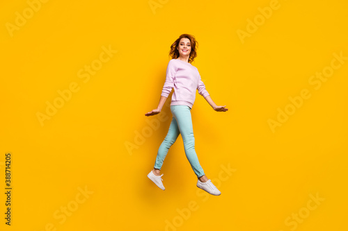 Full length photo of cheerful woman jump enjoy fall weekend vacation rest relax feel content wear casual style outfit isolated over vibrant color background