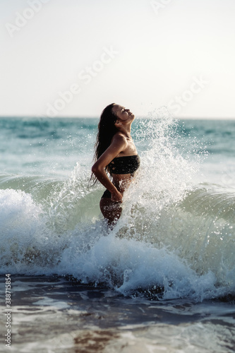 Beautiful tanned girl in a bikini enters the ocean