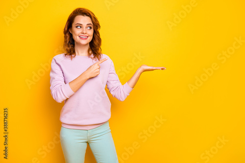 Photo of funny lady hold novelty indicating finger product on open arm advising sale low prices shopping wear pink pullover green pants isolated yellow color background