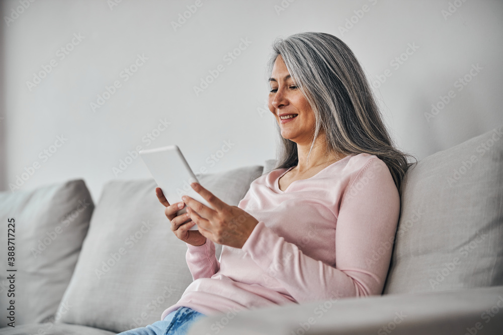 Charming elegant female looking to the screen modern device isolated on grey background Charming elegant female looking to the screen modern device isolated on grey background