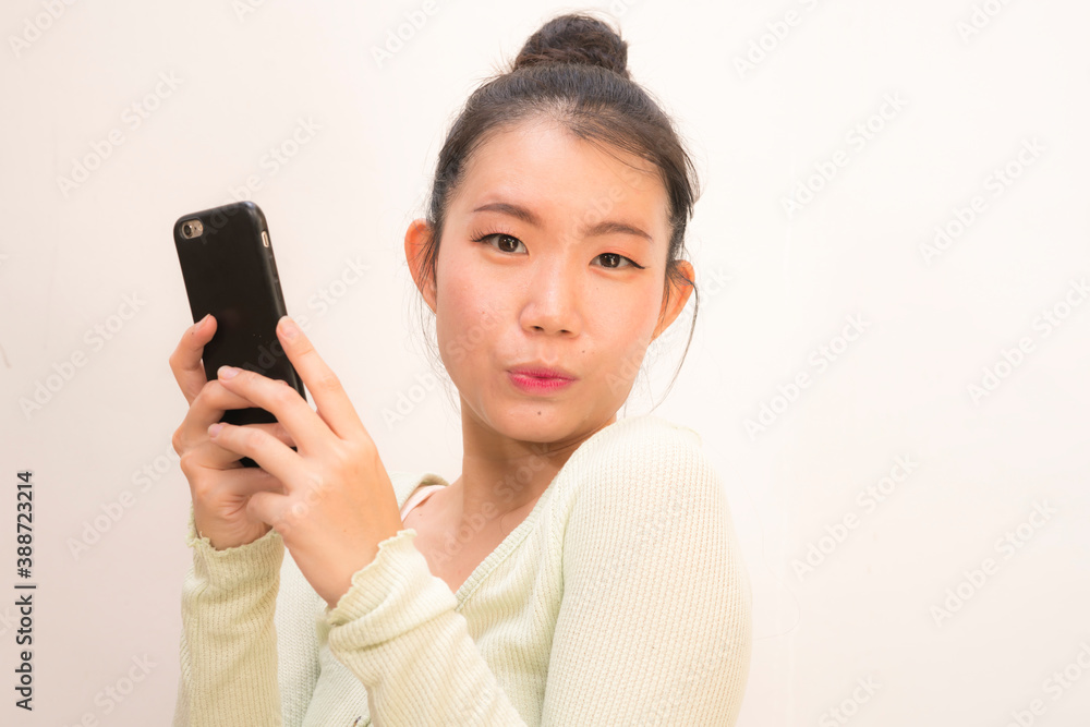 young attractive and sweet Asian Chinese woman posing happy and cheerful using internet mobile phone isolated on studio background in communication concept