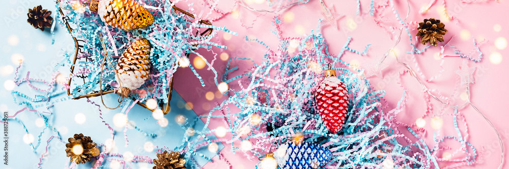 Naklejka premium Christmas web-banner. Colored cones in a gift boxes. Christmas lights. Blue-pink background. Flat lay, top view.