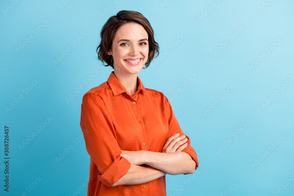 Photo of pretty attractive lady bobbed hairdo arms crossed self-confident person worker friendly smile white teeth good mood wear orange office shirt isolated blue color background - obrazy, fototapety, plakaty 