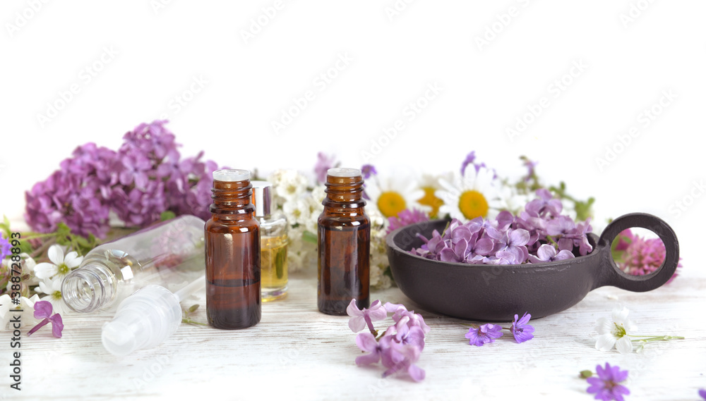 bottles of essentiel oil among pink flowers of lilac on white table bottles of essentiel oil among pink flowers of lilac on white table