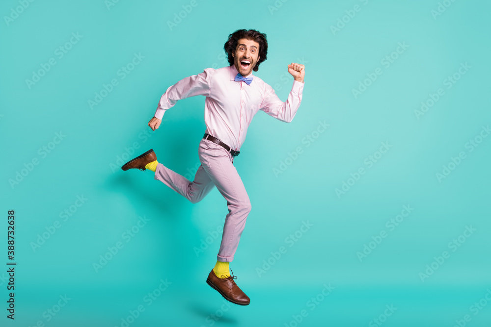 Full size portrait of funky running man jumping high dressed formalwear yellow socks isolated turquoise color background Full size portrait of funky running man jumping high dressed formalwear yellow socks isolated turquoise color background
