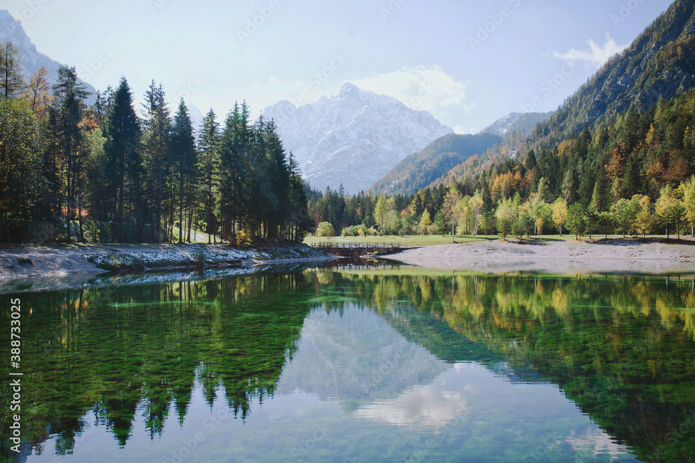 Beautiful view on green lake in the mountains against the colorful autumn forest in slovenian alps. Kranjska Gora, Slovenia.