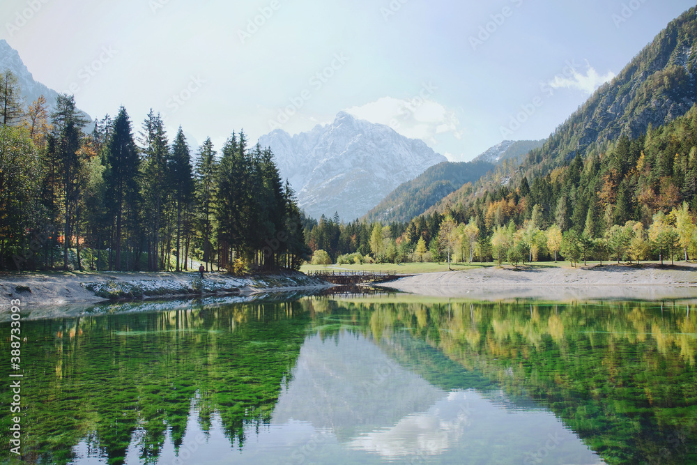 Beautiful view on green lake in the mountains against the colorful autumn forest in slovenian alps at Lake Jasna. 