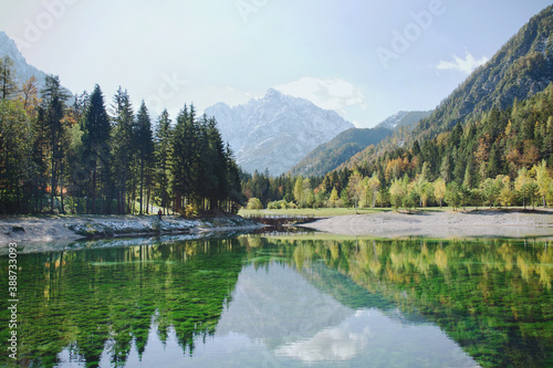 Beautiful view on green lake in the mountains against the colorful autumn forest in slovenian alps at Lake Jasna. 