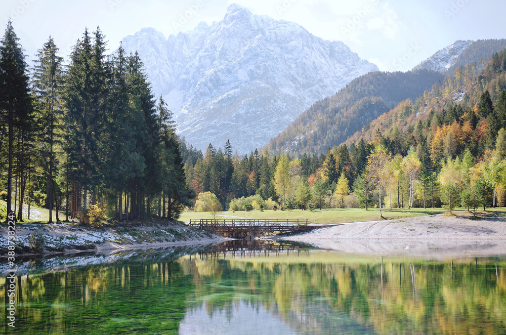 Beautiful view on green lake in the mountains against the colorful autumn forest in slovenian alps. 
