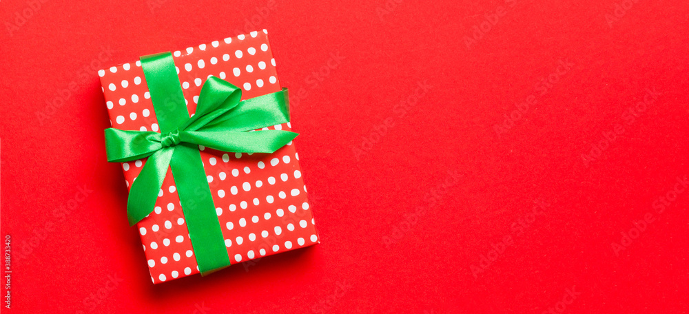 Obraz premium Top view Christmas present box with green bow on red background with copy space