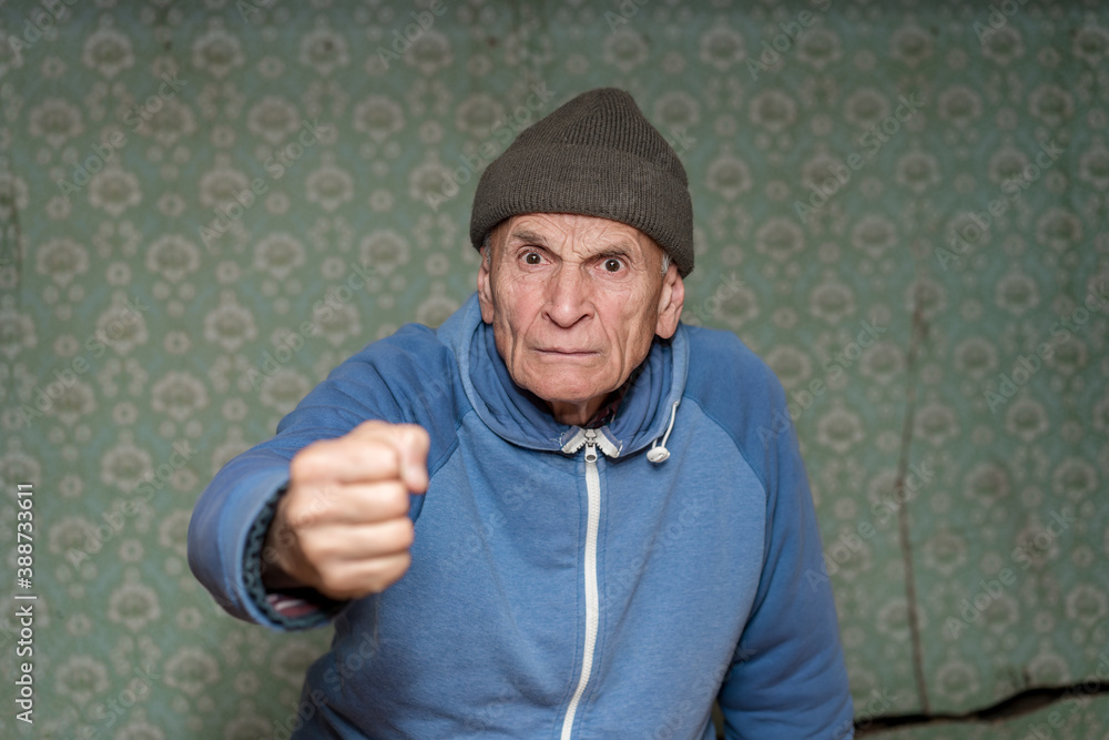 angry aggressive mature man with furious face wearing cap showing fist gesture