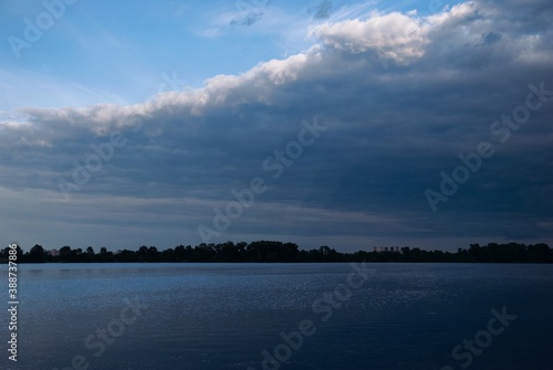 Dark blue clouds and blue sky, river, sunlight and sunshine , sun rays through clouds 