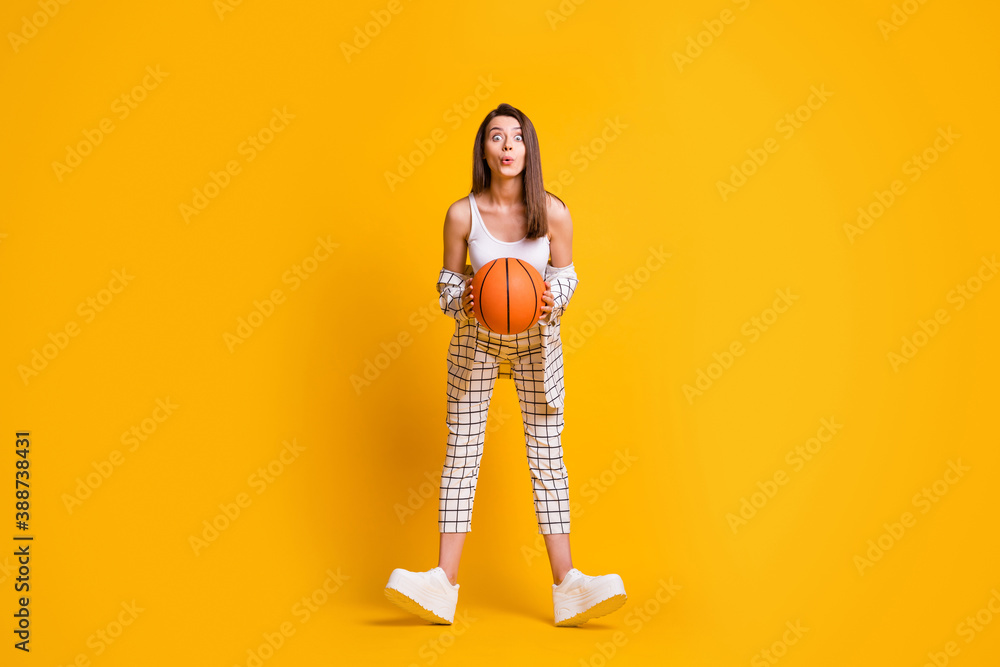 Photo of adorable attractive young woman hold game ball excited look ready play basketball wear singlet pants sneakers isolated bright yellow color background