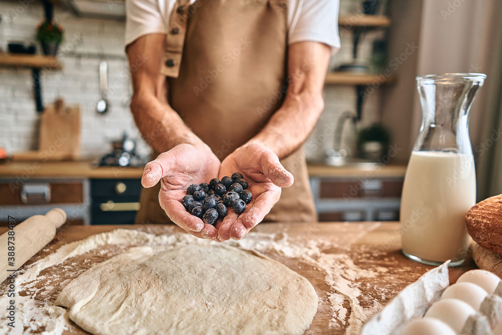 Man in an apron holding fresh berries for baking Man in an apron holding fresh berries for baking