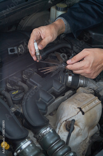 A man checks the spark gap in the spark plug with a probe, close-up