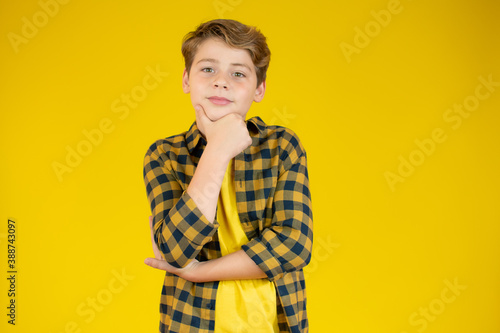 Portrait of a happy schoolboy with arms crossed, isolated on yellow