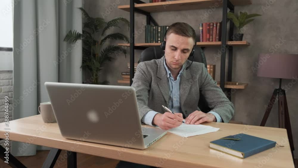 Smiling male student wear headset learning study with online tutor teacher. Talk conference calling do video chat learn language make notes sit at home office 4k Smiling male student wear headset learning study with online tutor teacher. Talk conference calling do video chat learn language make notes sit at home office 4k