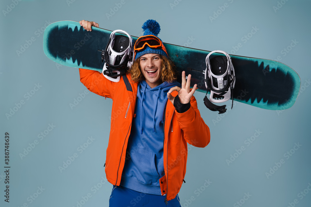 Handsome happy sportsman holding snowboard isolated