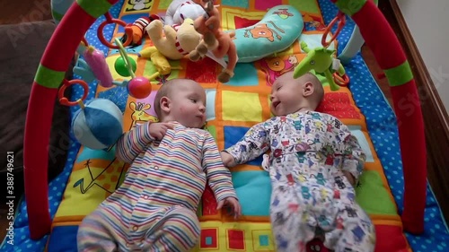 zenith shot of twin babies playing on activity blanket.