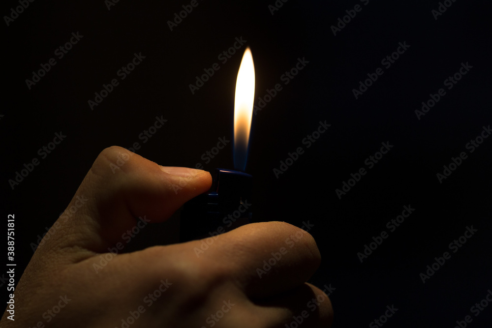 male hand holding a lighter with a large flame on a black background male hand holding a lighter with a large flame on a black background