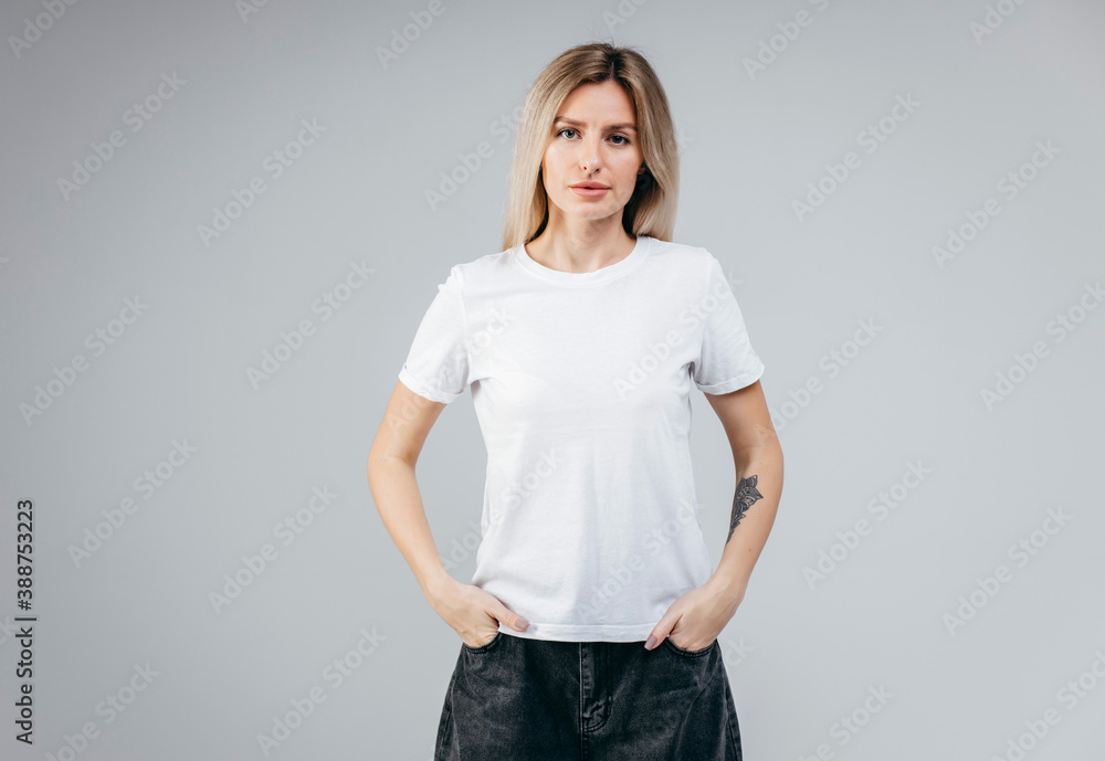 Stylish blonde girl wearing white t-shirt posing in studio - obrazy, fototapety, plakaty 