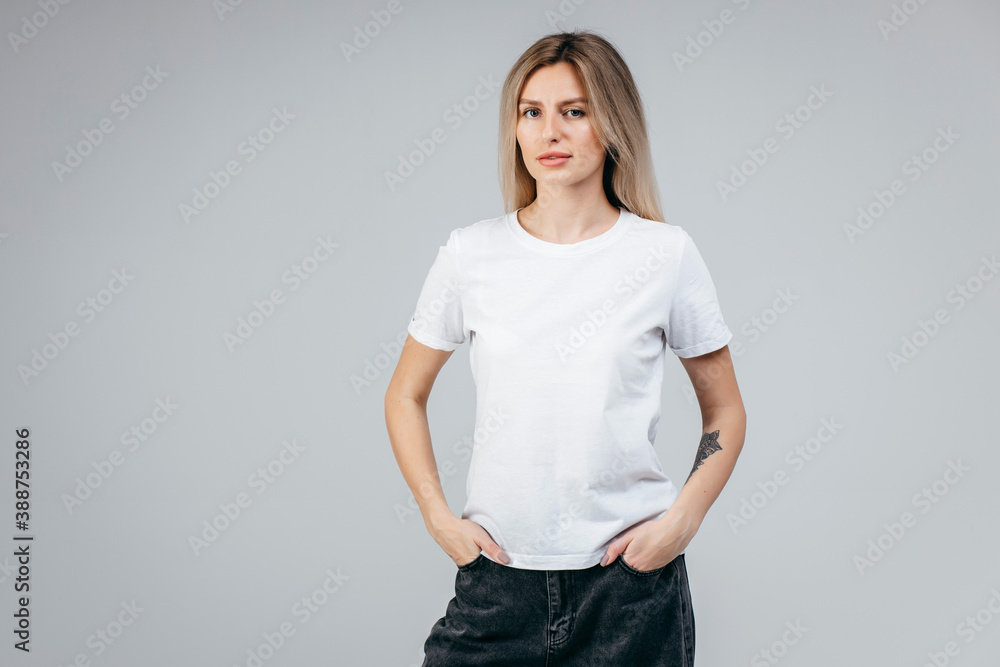 Stylish blonde girl wearing white t-shirt posing in studio - obrazy, fototapety, plakaty 