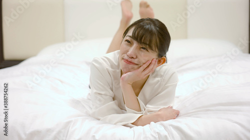 ホテルのベッドの上ではしゃいでいる女性 © aijiro
