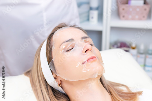 cosmetologist applies a hydrogel mask to a young woman on her face. The procedure by a beautician. Relax