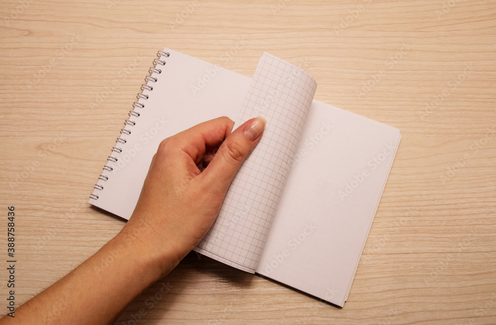 Left female hand flips through white notebook Left female hand flips through white notebook