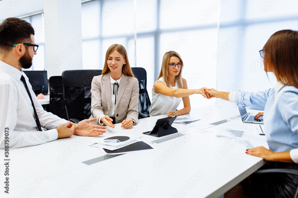 group of young businessmen working and communicating, sitting at an office table together with colleagues group of young businessmen working and communicating, sitting at an office table together with colleagues