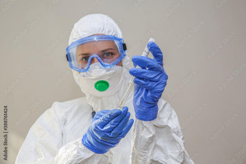 a young female doctor in a protective suit holds a smear on covid a young female doctor in a protective suit holds a smear on covid