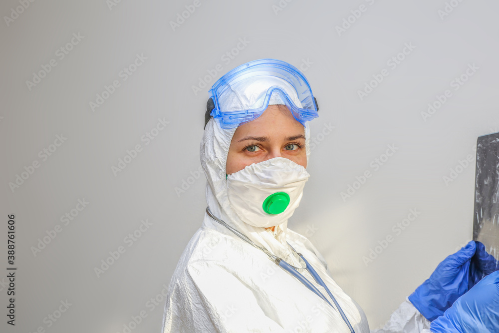 a young female doctor in a protective suit holds an x ray in her hands a young female doctor in a protective suit holds an x ray in her hands