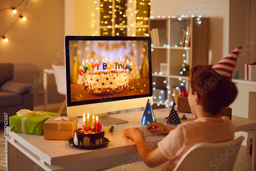 Canvas Print Little boy having online birthday party and looking at beautiful cake on compute