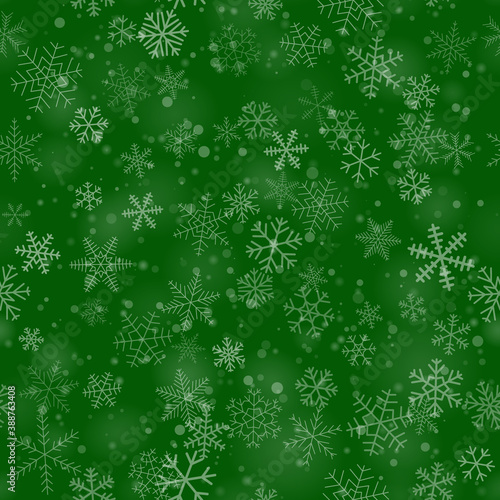 Christmas seamless pattern of snowflakes of different shapes, sizes and transparency, on green background