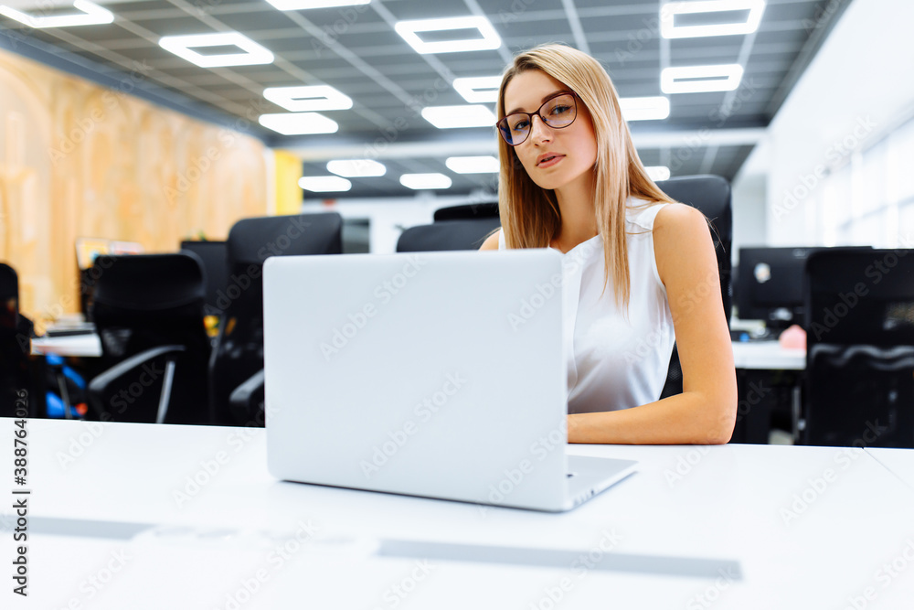 Successful attractive business woman using laptop while sitting at work table in office Successful attractive business woman using laptop while sitting at work table in office
