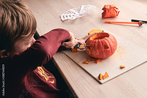 Halloween, decoration and holidays ideas- close up of kid with knife carving pumpkin or jack-o-lantern. 6 years boy has homefamily fun activity. Mom spending time with son together photo