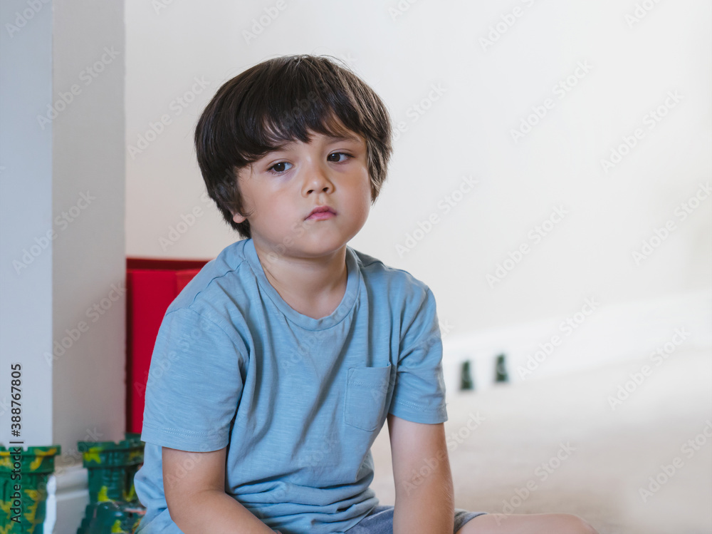 Dramatic portrait tired kid siting alone and lookig out deep in throught, Bored child siting on floor with unhappy face, Lonely Young boy with sad face sitting alone in coner, Health metal concept Dramatic portrait tired kid siting alone and lookig out deep in throught, Bored child siting on floor with unhappy face, Lonely Young boy with sad face sitting alone in coner, Health metal concept