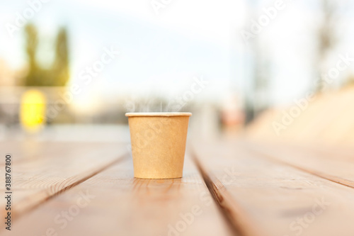 Cardboard cup with hot coffee on urban wooden terrace. Kartonbecher mit heißem Kaffee auf Holz Terrasse im urbanen Gebiet.