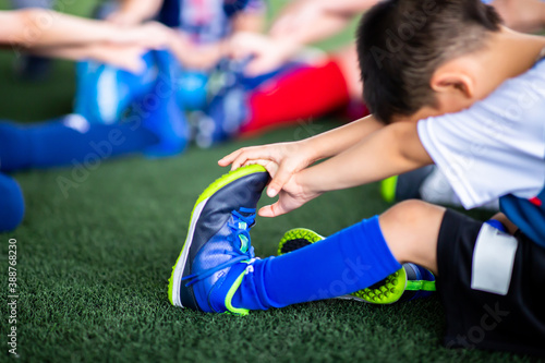 Selective focus to Kid soccer players are stretching their hands to catch their feet to warming up and stretching the body and foot
