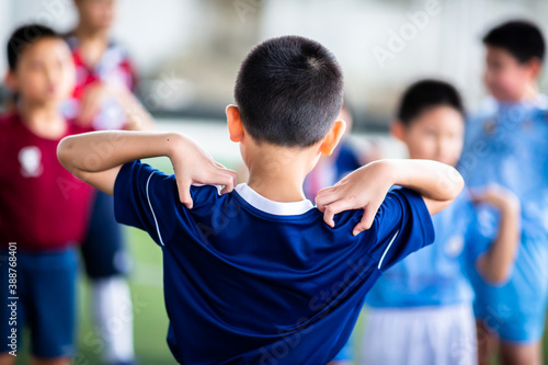 Selective focus to Soccer player is standing and catch the shoulder to warming up and stretching the body