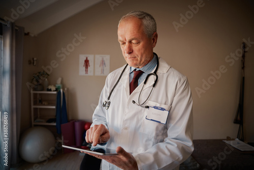 Bilde på lerret Senior male medical professional wearing labcoat and stethoscope using digital t