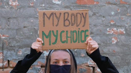 Young woman protester holds cardboard with MY BODY MY CHOICE sign. Girl protesting against anti-abortion laws. Feminist women power march.Feminism concept equal opportunity rights independence freedom
