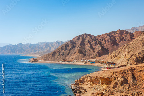 Sunny resort beach at the coast shore of Red Sea in Dahab, Sinai, Egypt, Asia in summer hot. Famous tourist destination Blue Hole near of Sharm el Sheikh. Bright sunny light