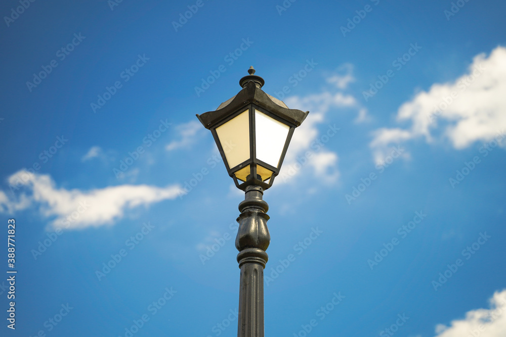 Close-up of the vintage street lantern against clear blue sky with clouds.